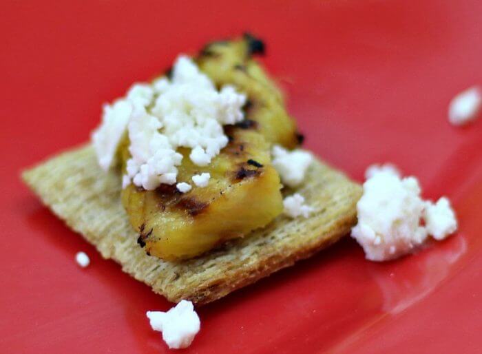 Add feta cheese to the top of the pineapple on the cracker