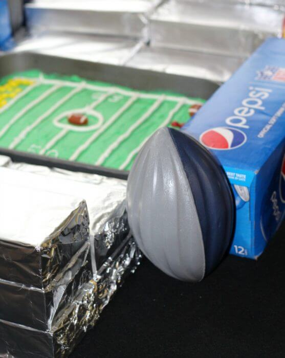 Stack up the foil wrapped blocks to make the stands and put the cases f soda on the end zone side and a football in each corner